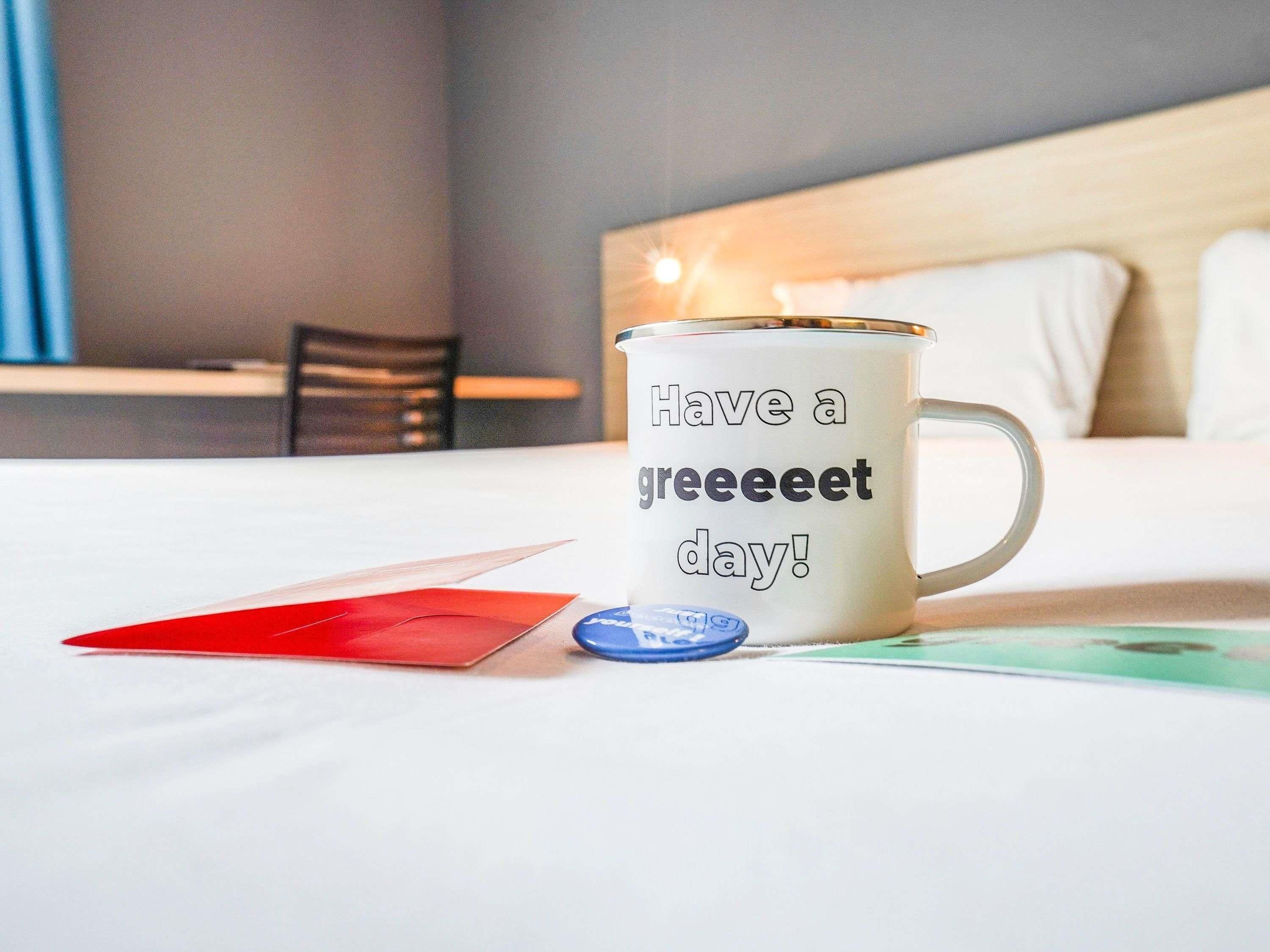Una taza con un mensaje sobre una cama de hotel.