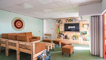 A modern living room with a sofa, ottoman, and a television displaying 'greet'.
