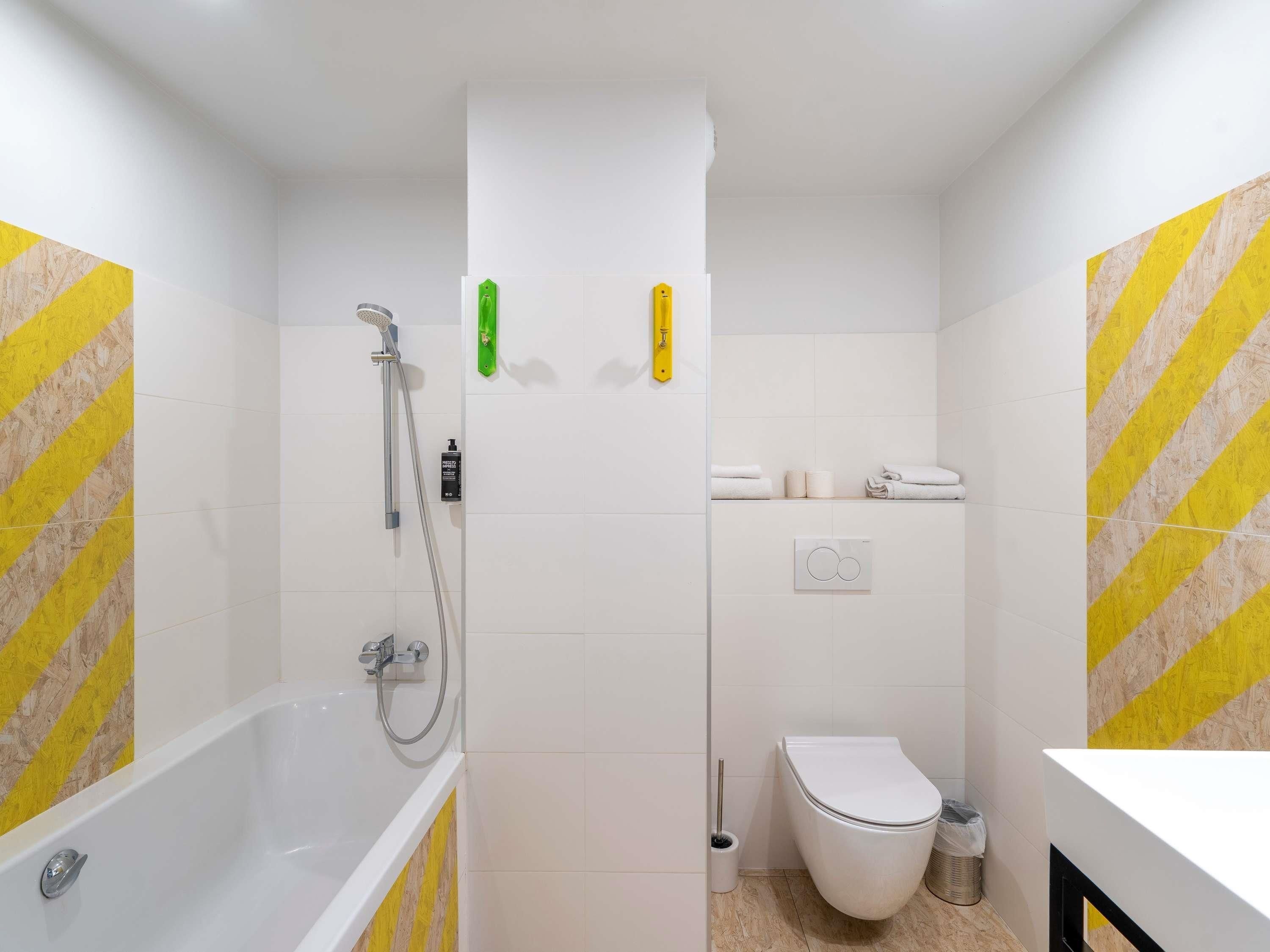 Un baño con bañera, ducha, inodoro y toallero.