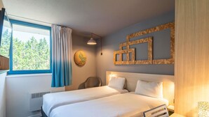 Une chambre d’hôtel avec deux lits, un bureau, une chaise, une fenêtre avec des rideaux, une horloge murale et un panneau décoratif en bois.