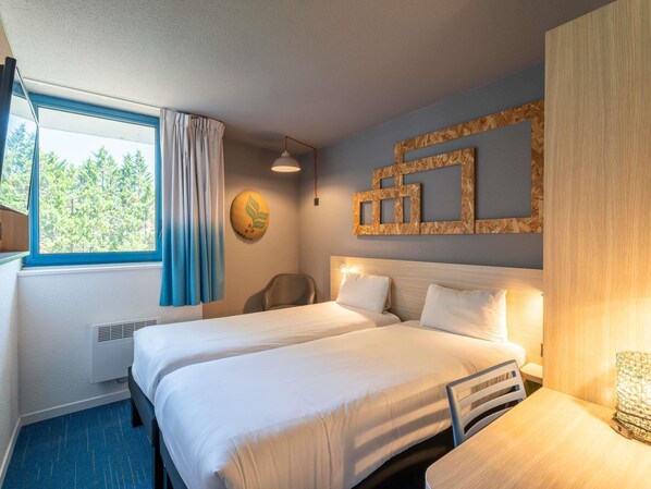 Habitación de hotel con dos camas, un escritorio, una silla, una ventana con cortinas, un reloj de pared y un panel de madera decorativo.