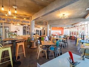 An interior with tables, chairs, a wooden counter, and a sign reading 'the great place'.