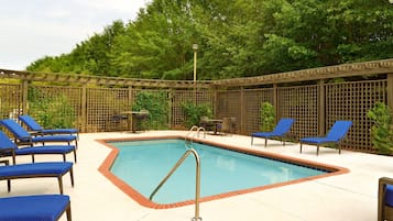 Una piscina al aire libre, sillones reclinables de piscina