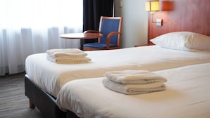 A hotel room with two beds, a chair, a small table, and a lamp. - Westlake Hotels Amsterdam (Amsterdam)