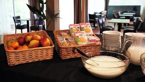 A breakfast buffet with fruit baskets, cereal boxes, and milk. - Westlake Hotels Amsterdam (Amsterdam)