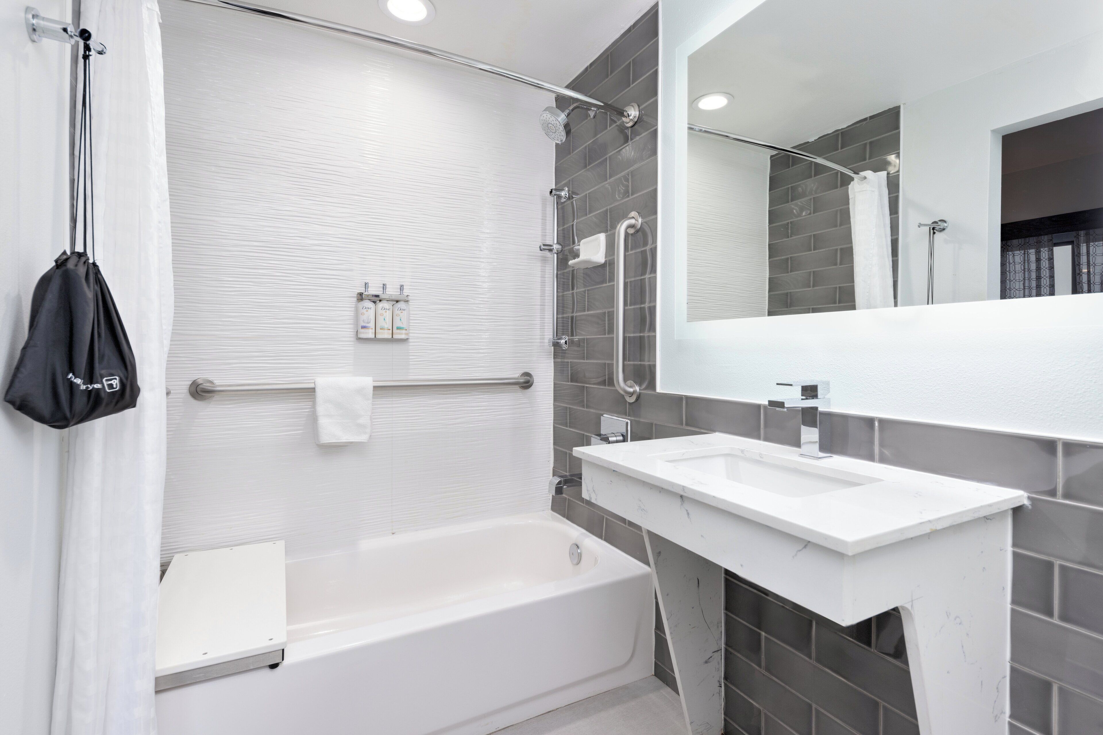 A modern bathroom with a bathtub, a white sink, and a large mirror.