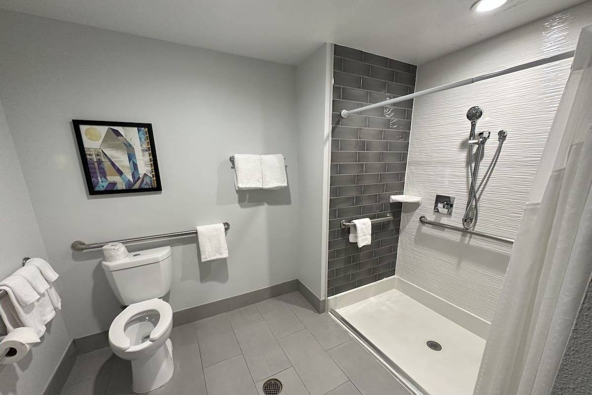 A modern bathroom with a toilet, a shower with a glass door, and a towel rack.