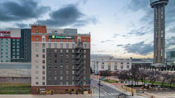 A multi-story hotel with a fire escape, a Holiday Inn Express sign, and a view of a tall tower and other buildings in the background.