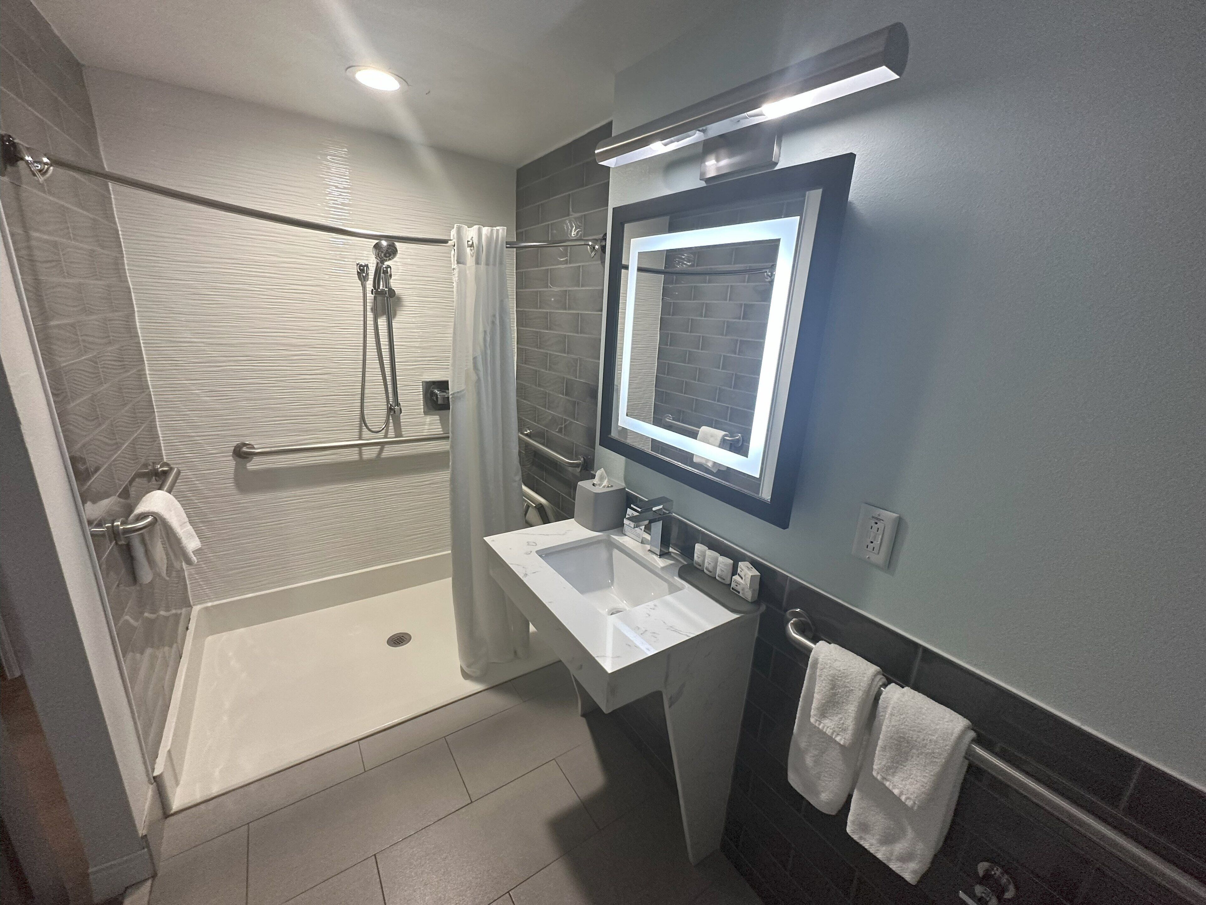 A modern bathroom with a walk-in shower, a vanity with a mirror, and a bathtub.