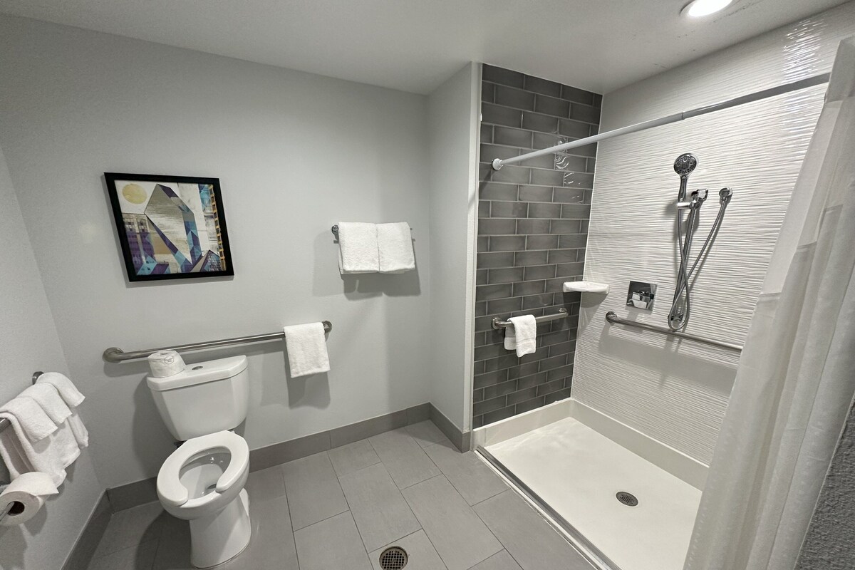 Un baño moderno con inodoro, ducha con puerta de cristal y un perchero para toallas.