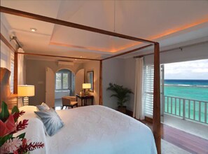 A four-poster bed with a view of the ocean.