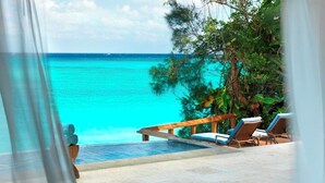 A poolside area with lounge chairs and a view of the ocean.