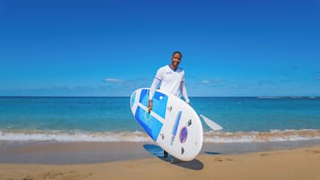 A person holding a surfboard on a beach.