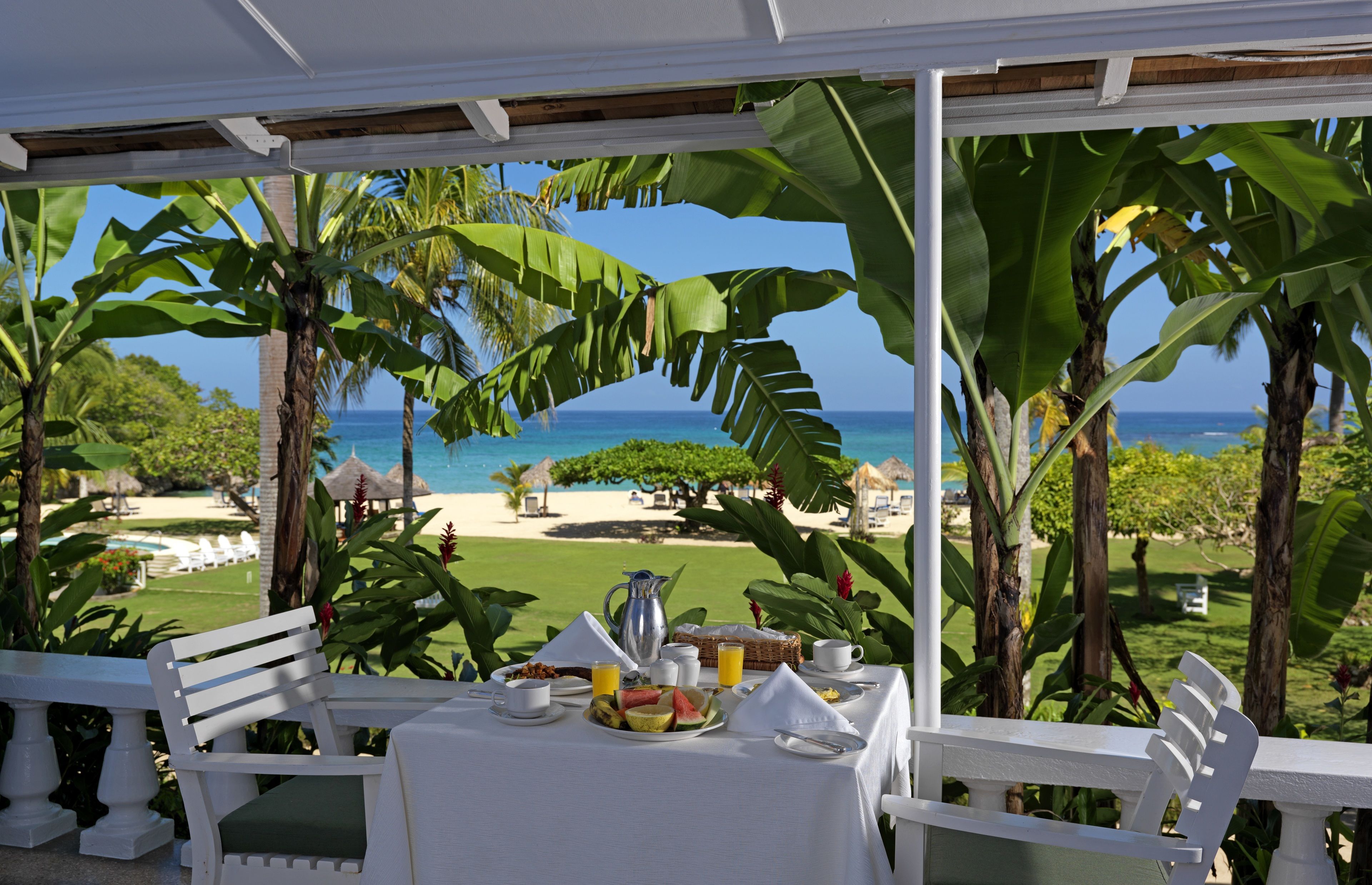 Una mesa lista para el desayuno con vista a la playa y al océano.