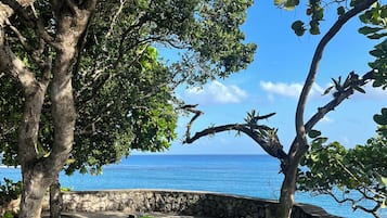 Un espace extérieur dallé de pierres, équipé de tapis de yoga et offrant une vue sur l’océan.