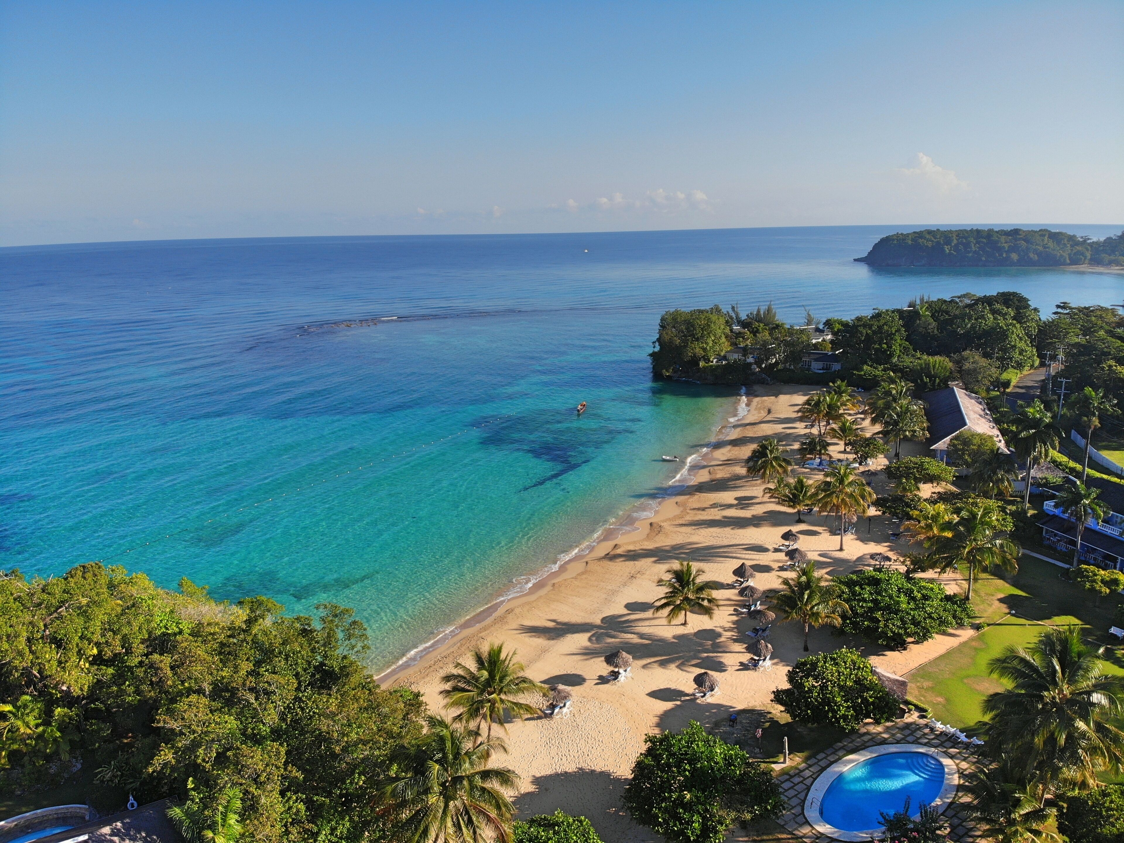 A beach resort with a pool, palm trees, and ocean views.