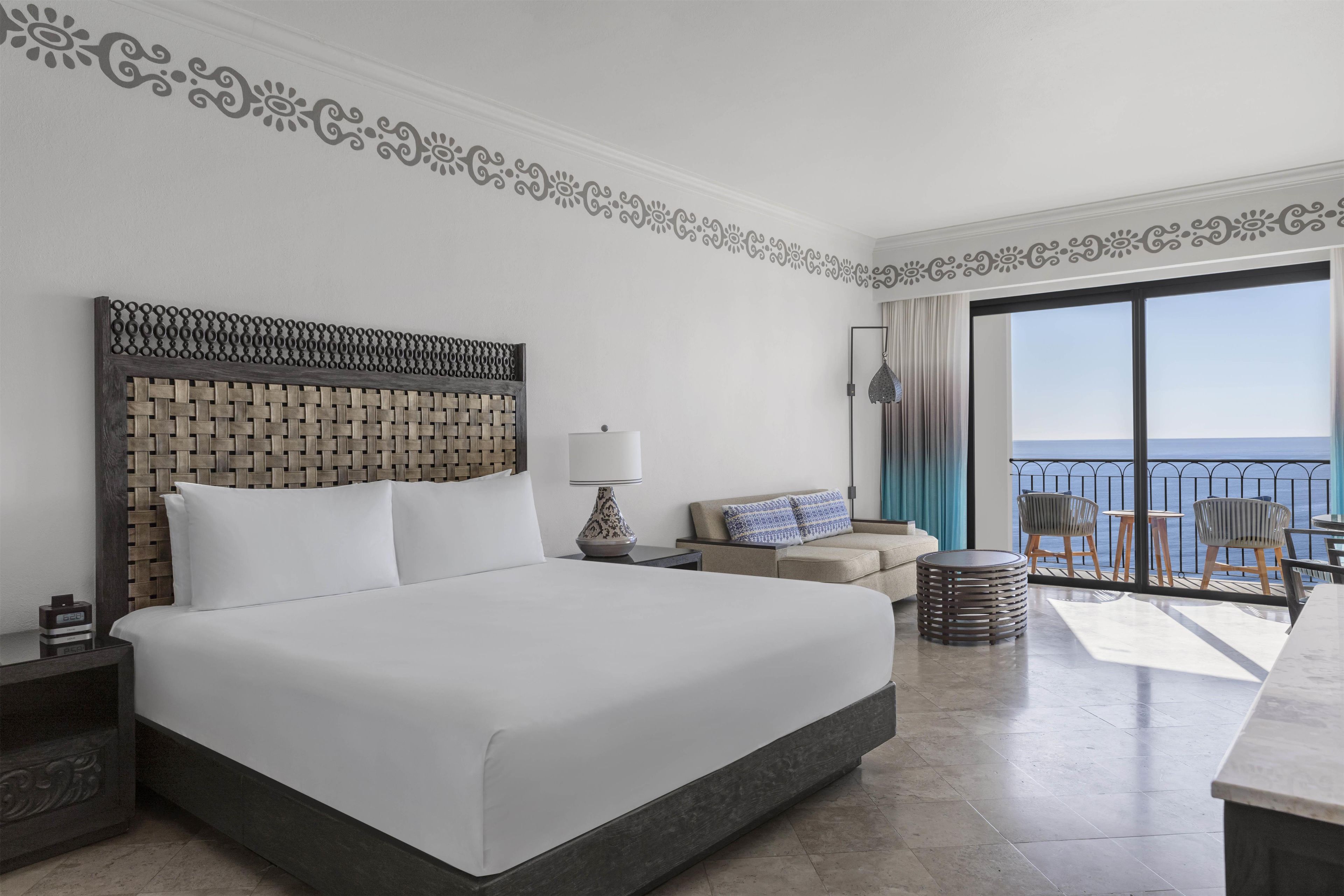 Una camera d'albergo con un letto grande, un divano, un tavolino e un balcone vista mare.