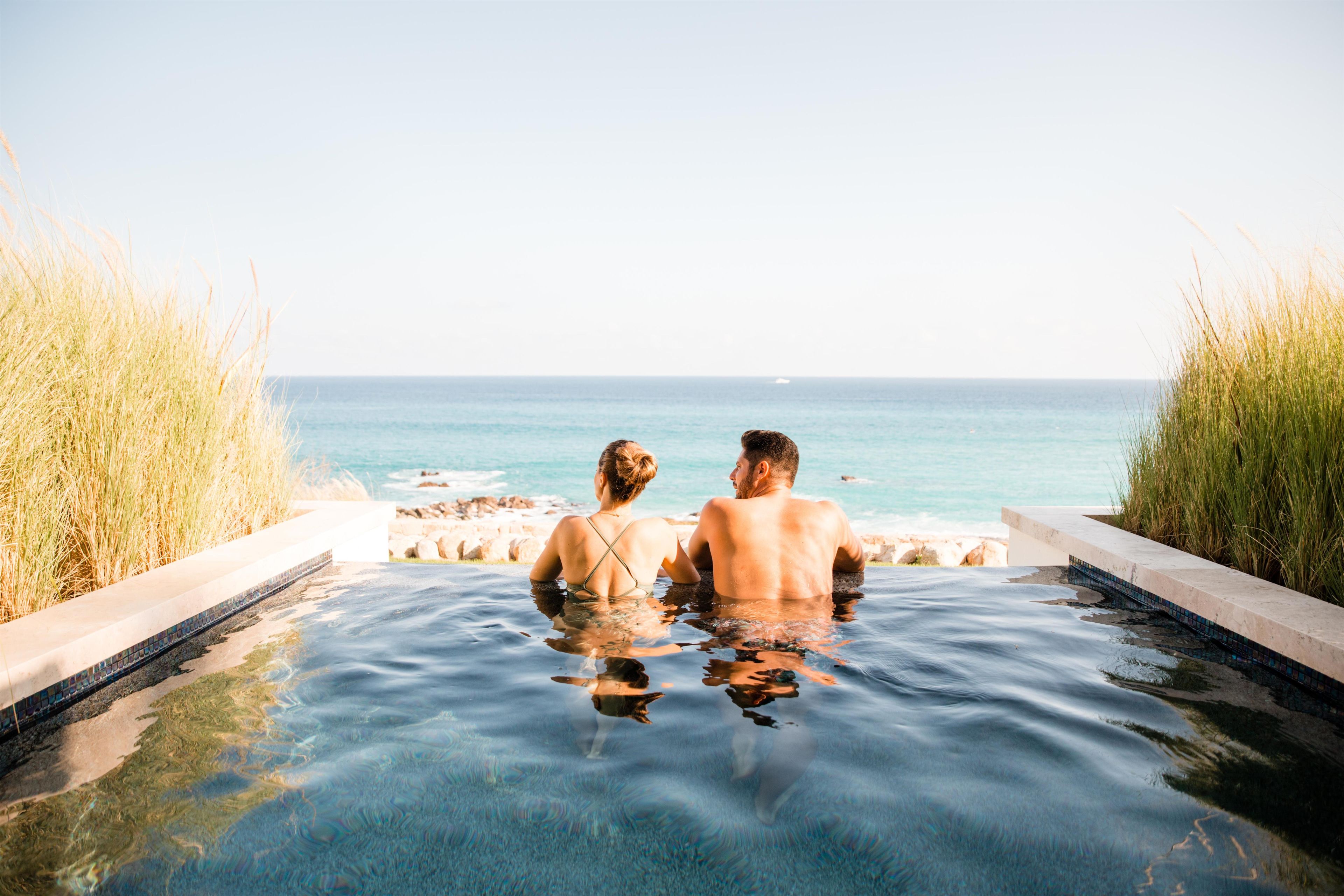 A couple sitting in a hot tub with a view of the ocean.