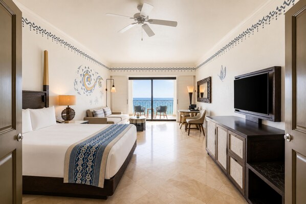 A hotel room with a bed, a desk, a TV, and a balcony with a view.