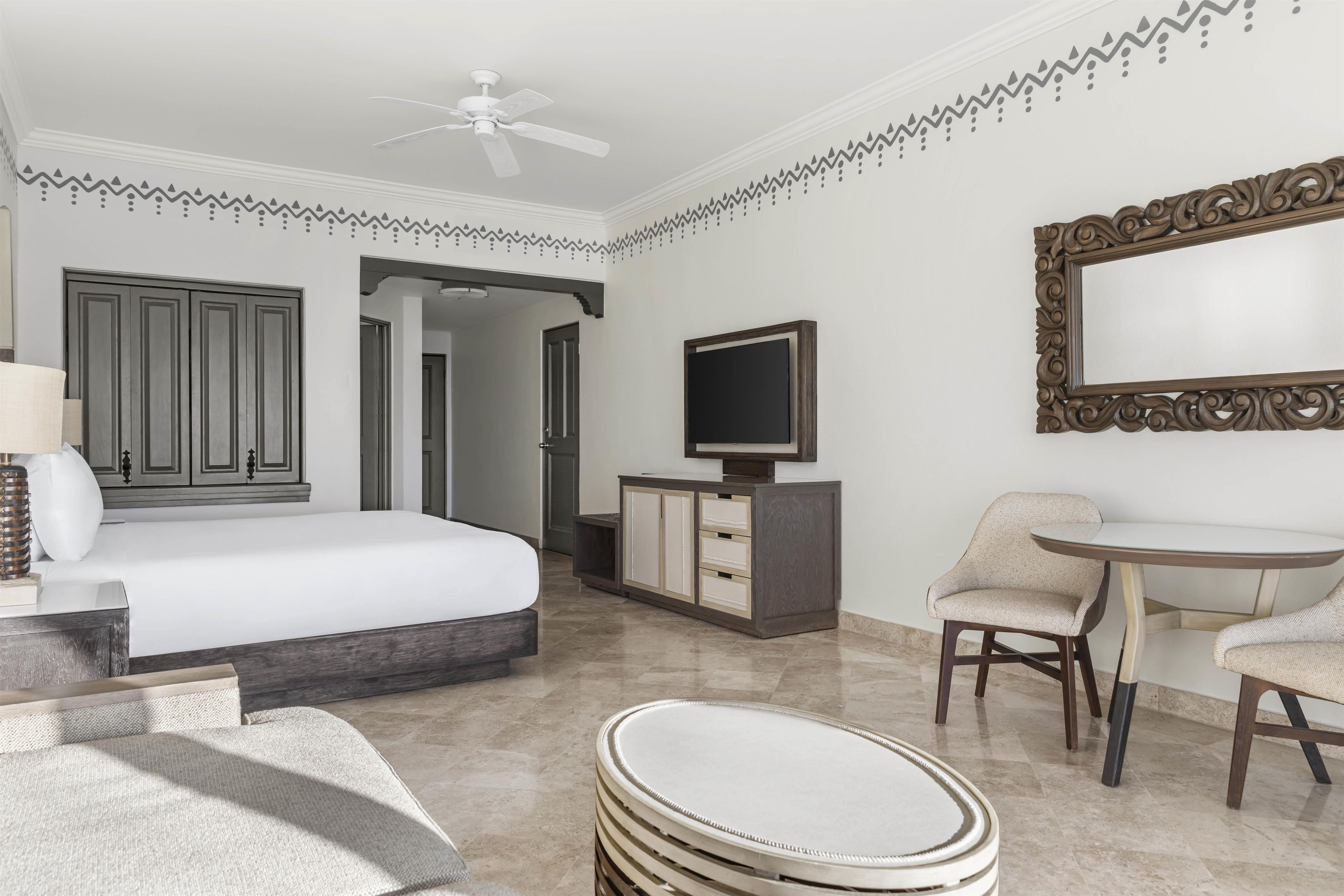 A hotel room with a bed, a desk, a chair, a television, and a cabinet.