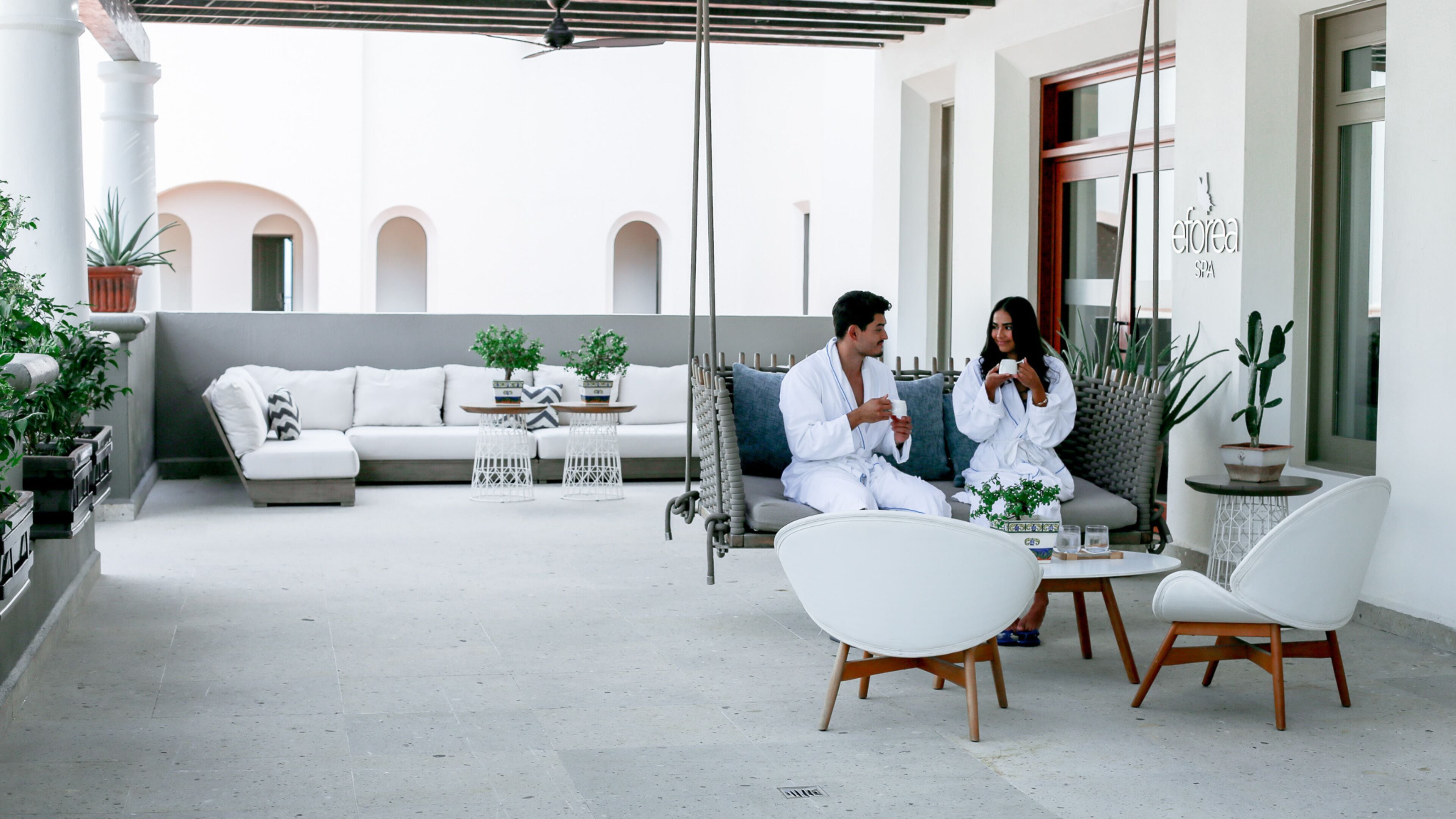 A modern outdoor seating area with a sofa, two chairs, and a small table.