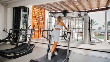 Un gimnasio con cintas de correr, máquinas de pesas y vista al océano.