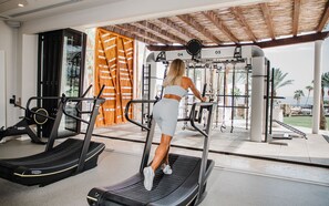 A gym with treadmills, weight machines, and a view of the ocean.