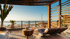 A beachside lounge with a view of the ocean, wooden deck, and lounge chairs. - Hilton Los Cabos (San José del Cabo)