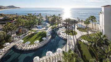 Un resort con una piscina grande, palmeras y vistas al océano.