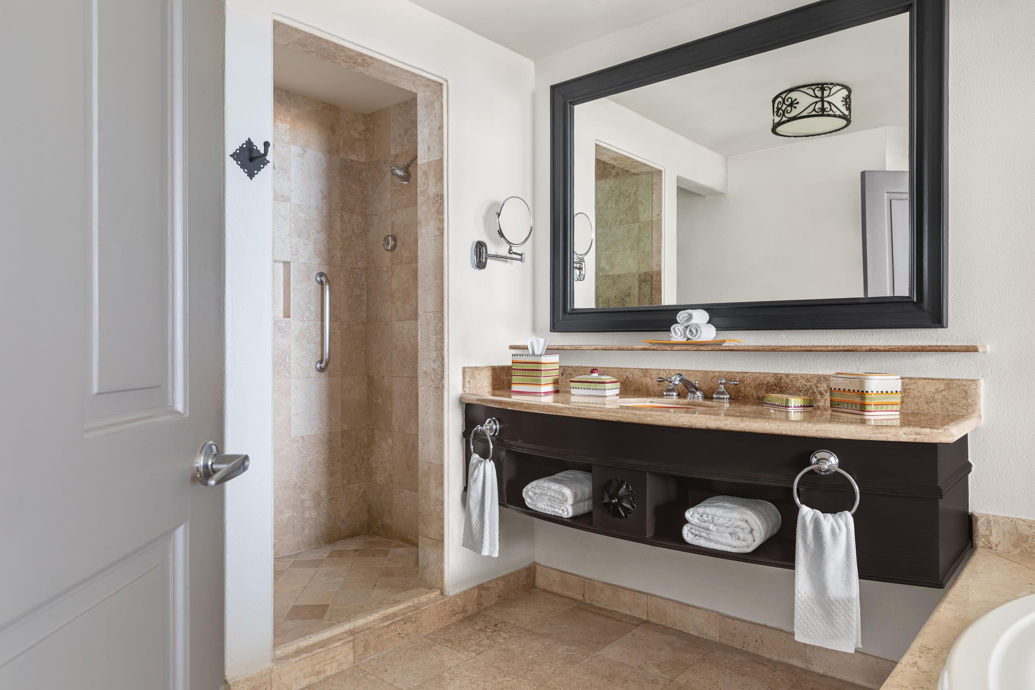 A bathroom with a shower, a sink with a mirror, and a towel rack.