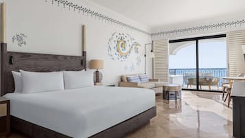 Ein Hotelzimmer mit einem großen Bett, einer Couch, einem Essbereich mit Tisch und Stühlen sowie einem Balkon mit Blick.