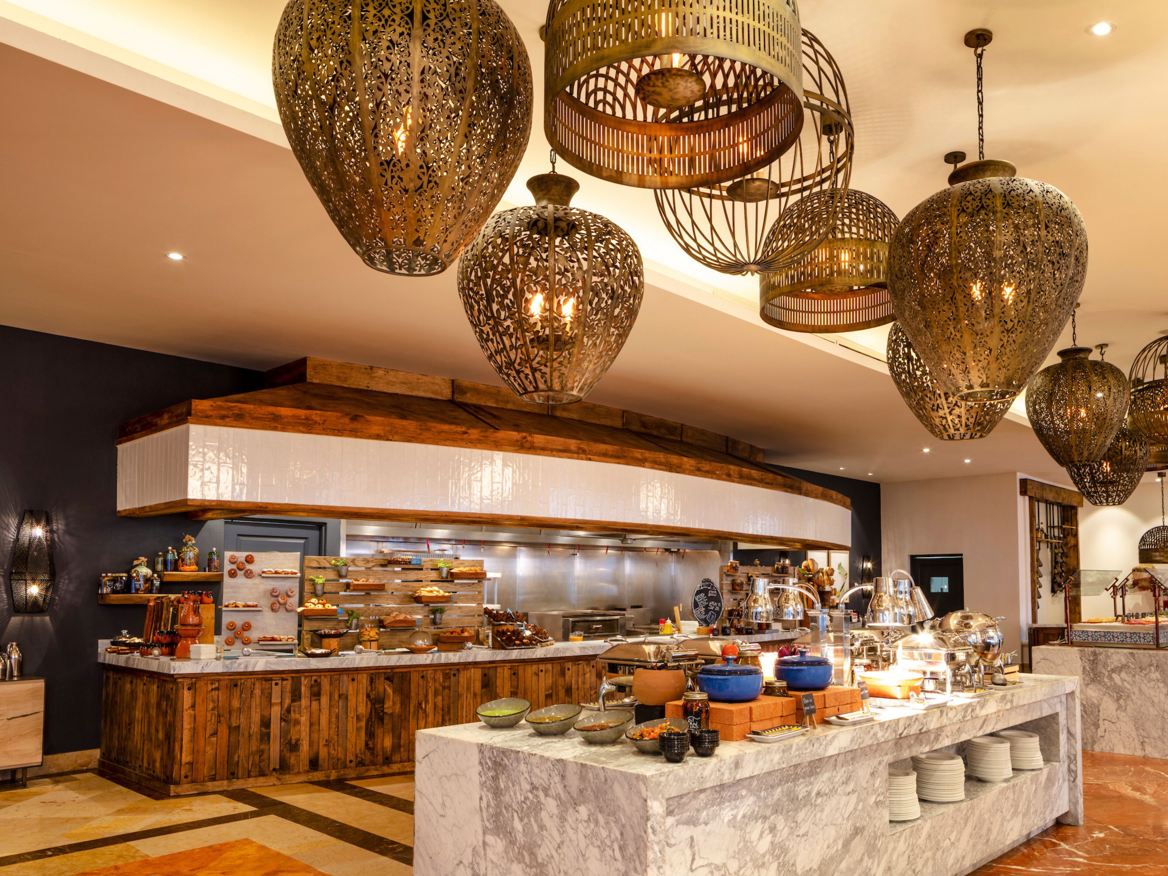 Una cocina moderna con encimera de mármol, detalles de madera e iluminación decorativa colgante.