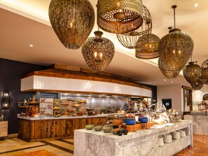 A modern kitchen with a marble countertop, wooden accents, and hanging decorative lights. - Hilton Los Cabos (San José del Cabo)