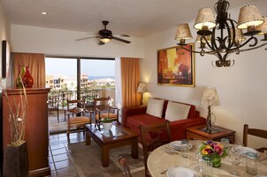 A hotel room with a balcony, a dining area, a sofa, and a chandelier.