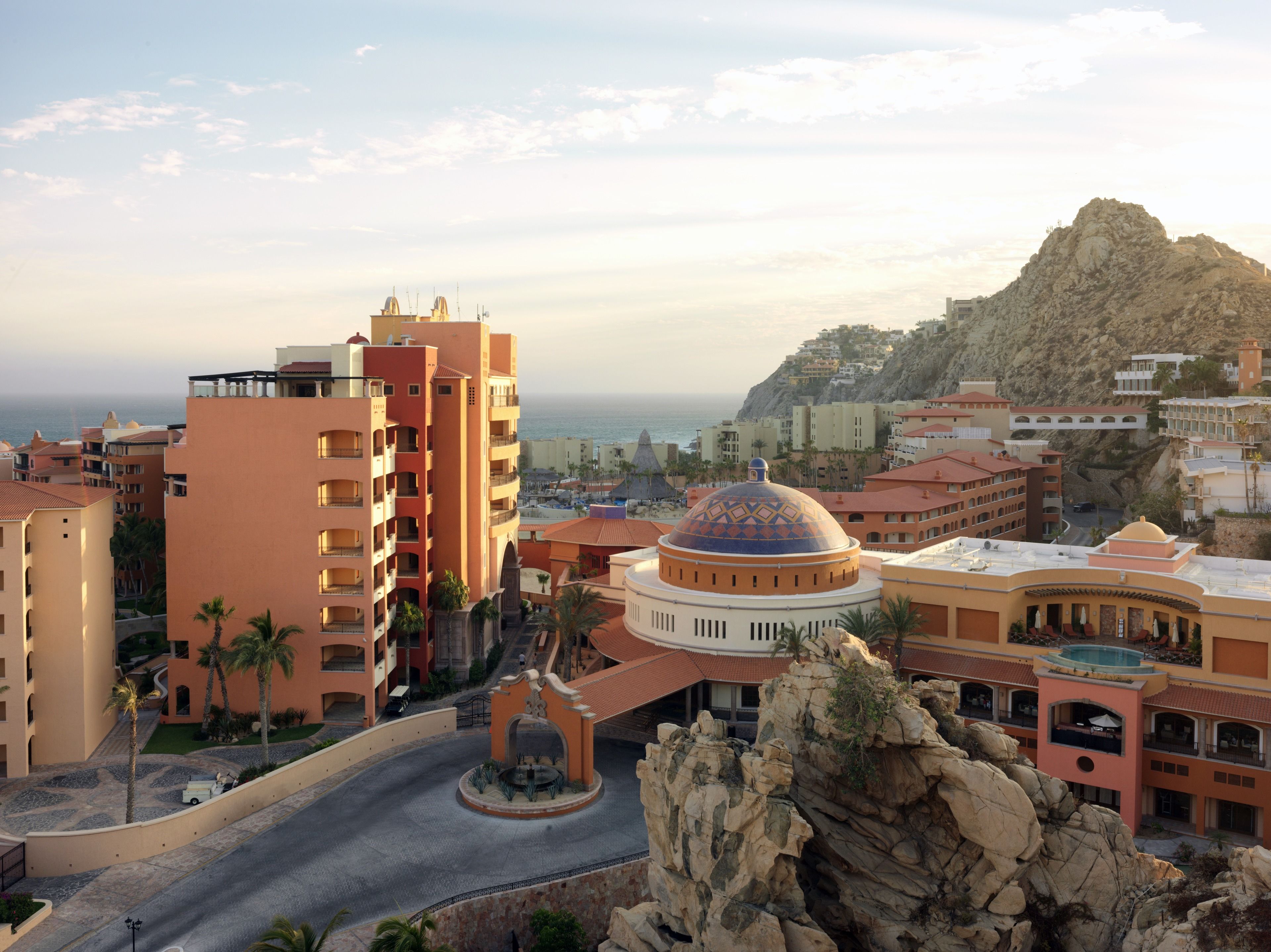 A coastal resort with multiple buildings, a central roundabout, and a prominent rock formation.
