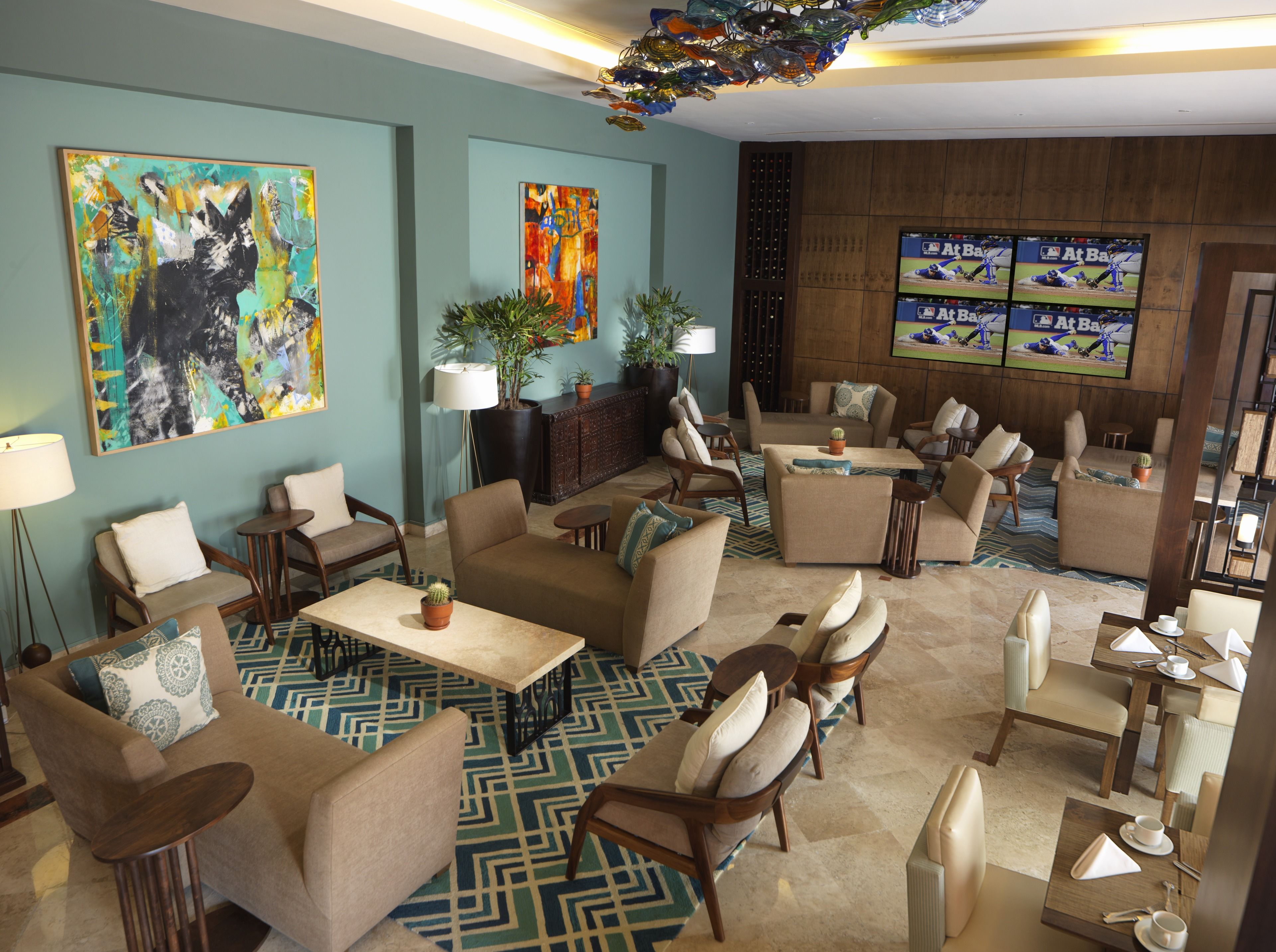 A spacious lobby with multiple seating areas, a large TV screen, and artwork on the walls.