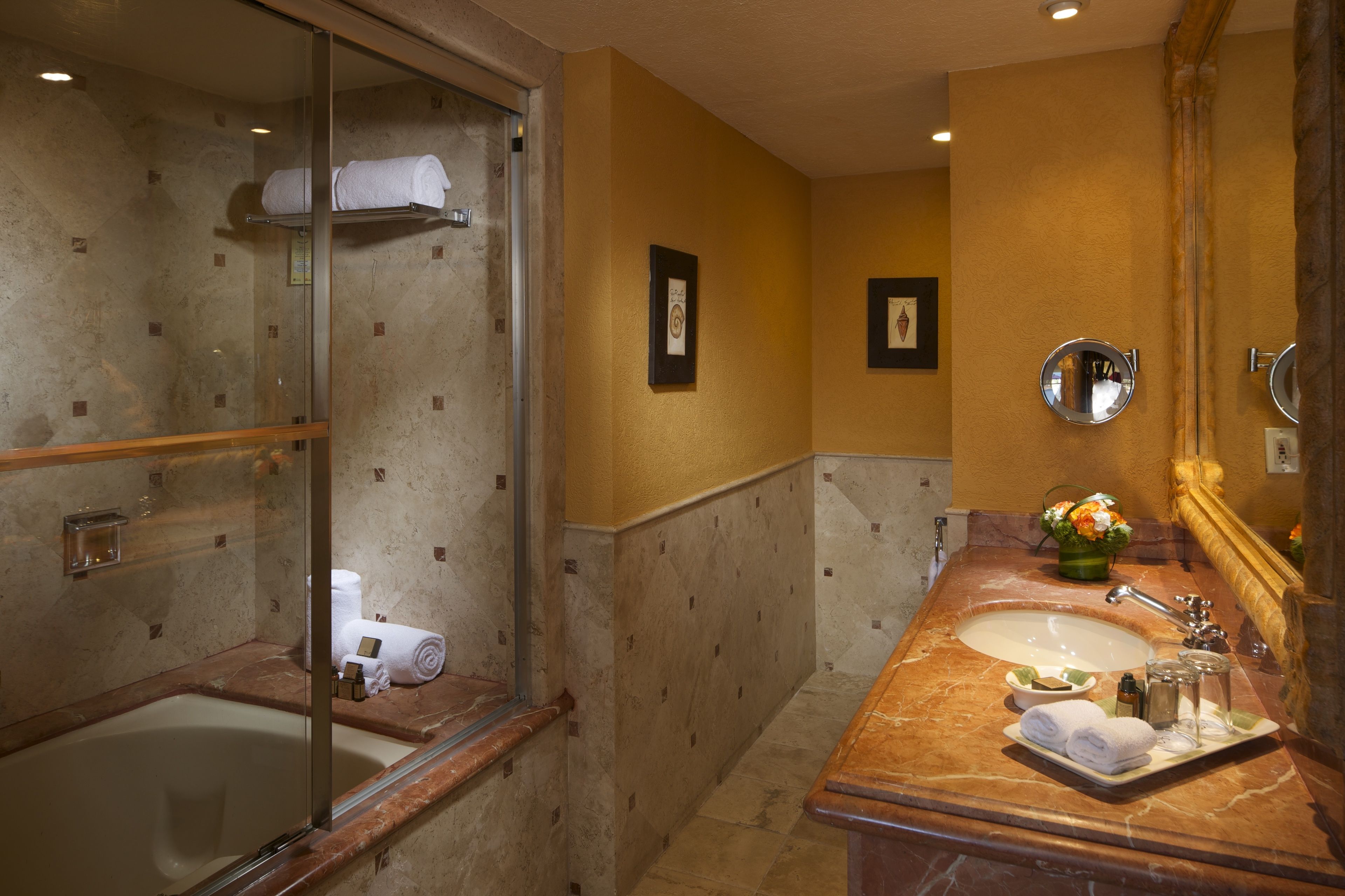 Une salle de bain avec une douche à parois de verre, un lavabo en marbre et un miroir.