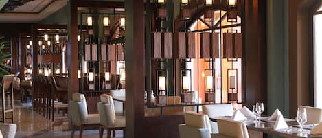 A hotel lobby with a modern design, featuring a reception desk, seating area, and a staircase.