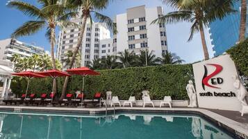 Een buitenzwembad, ligstoelen bij het zwembad