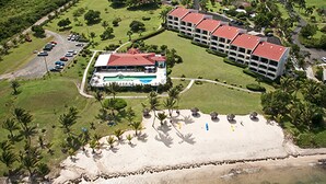 An aerial view of a hotel with a large building, a beach, and a parking area. - Club St. Croix Beach & Tennis Resort by Antilles Resorts (Christiansted)