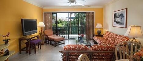 A living room with a television, seating, and a balcony with curtains.
