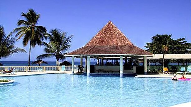 A swimming pool with a gazebo, palm trees, and a view of the ocean. - Starfish Tobago Resort (Plymouth)