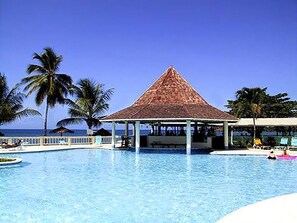 A swimming pool with a gazebo, palm trees, and a view of the ocean. - Starfish Tobago Resort (Plymouth)