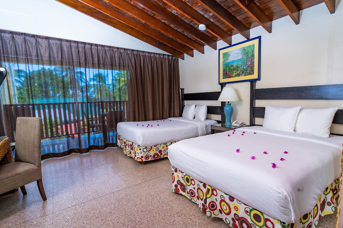 A hotel room with two beds, a chair, a nightstand, and a window with curtains.