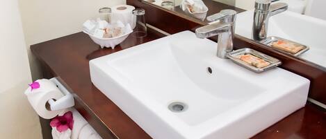 Une salle de bain avec un lavabo blanc, un miroir et des articles de toilette.
