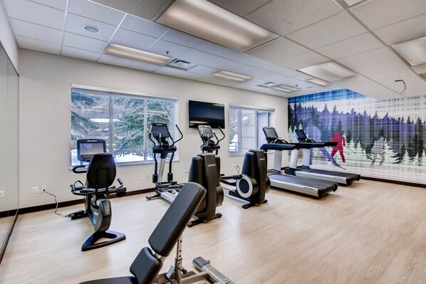 A gym with treadmills, elliptical machines, and weight benches.