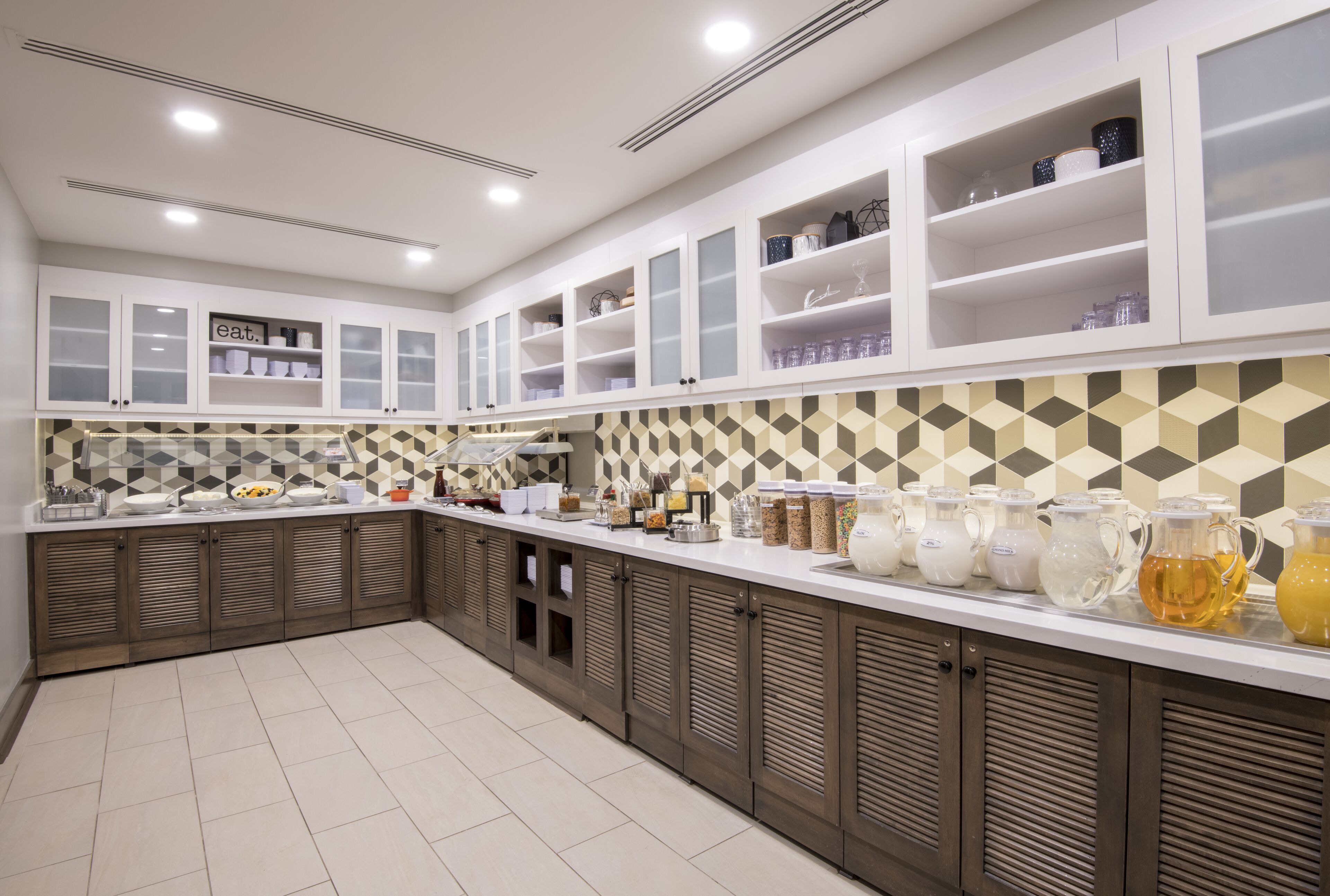 A modern kitchen with white cabinets, a patterned backsplash, and a countertop with jars and containers.