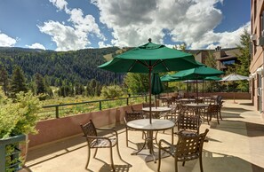 An outdoor patio with tables and chairs, green umbrellas, and a scenic mountain view. - Hyatt Place Keystone / Dillon (Keystone)