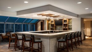 Una cocina moderna con una isla central, taburetes de bar y un ventanal grande.