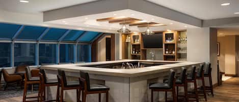 Una cocina moderna con una isla central, taburetes de bar y un ventanal grande.